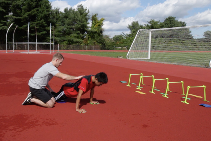 Trainer teaching autistic child proper pushup form.